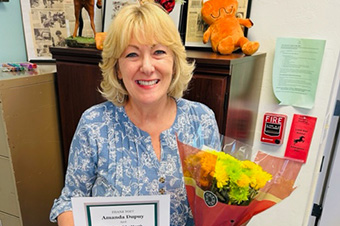 Amanda Dupuy holding Teacher of the Month certificate and flowers