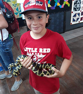 Boy wearing a red school shirt and holding a snake