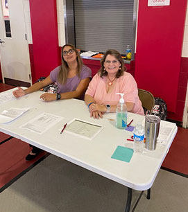 Two teachers sitting at a sign-up table