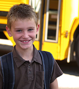 student in front of a school bus