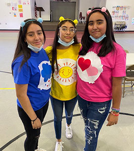 Three students wearing colored shirts
